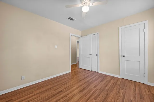 a view of a room with wooden floor and a ceiling fan