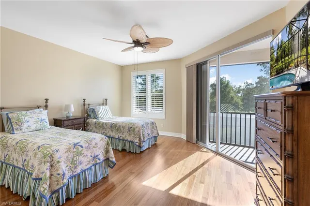 a bedroom with two beds chandelier and a window