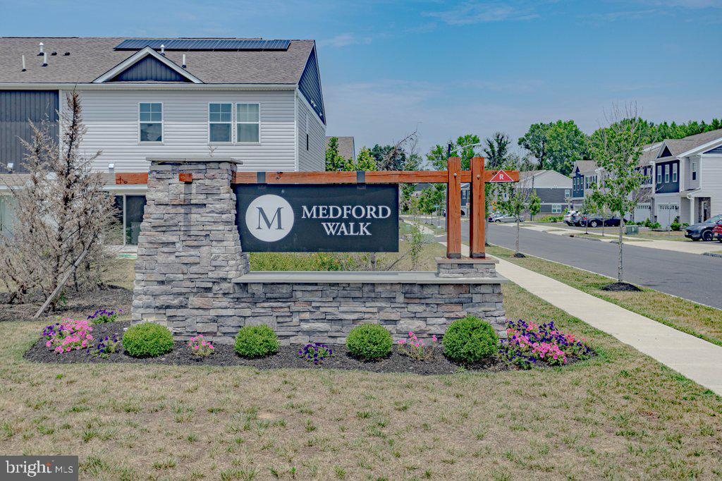 a view of a street with flower plants and wooden fence