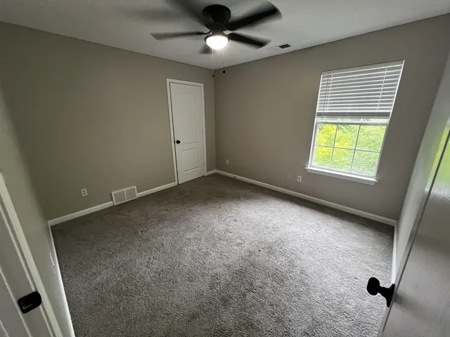 an empty room with windows and fan