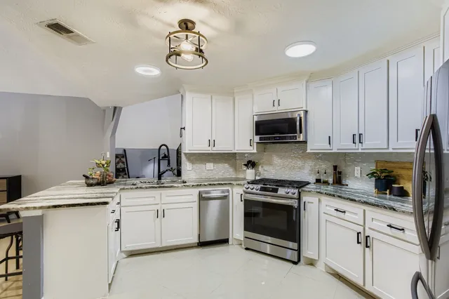 a kitchen with white cabinets appliances and a sink