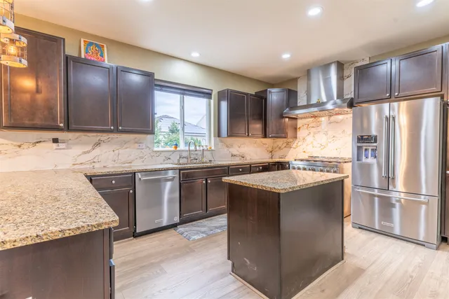 a kitchen with kitchen island granite countertop a sink stove and refrigerator