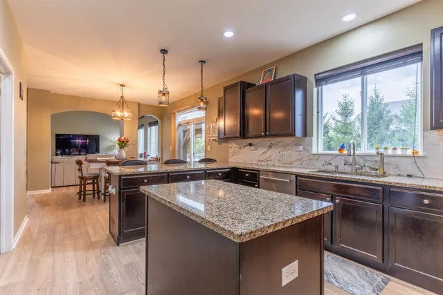 a kitchen with a stove a sink dishwasher a kitchen island with wooden cabinets and floor