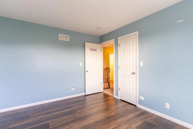 a view of an empty room with wooden floor and closet