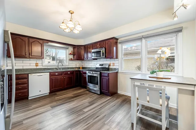 a kitchen with stainless steel appliances kitchen island granite countertop wooden floors and wooden cabinets