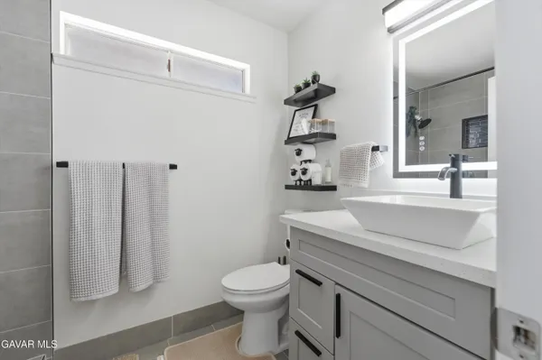 a bathroom with a granite countertop toilet sink and mirror