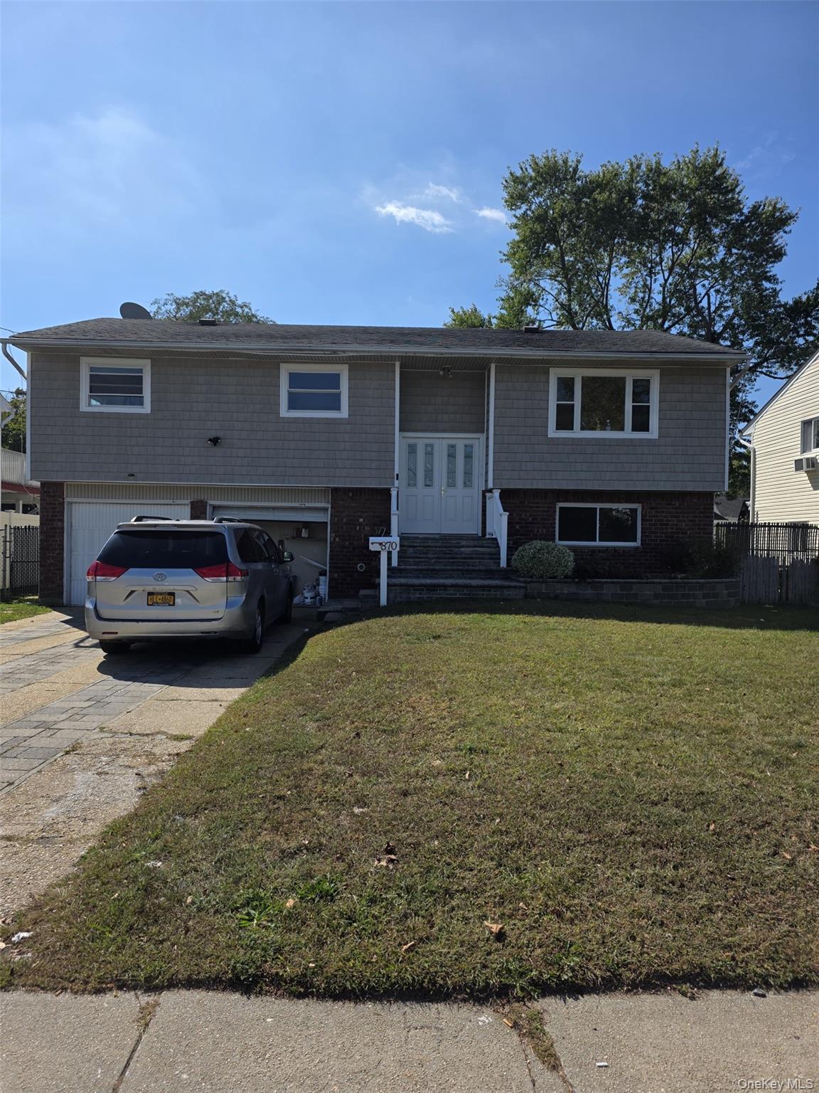 Bi-level home featuring brick siding, concrete driveway, and a garage