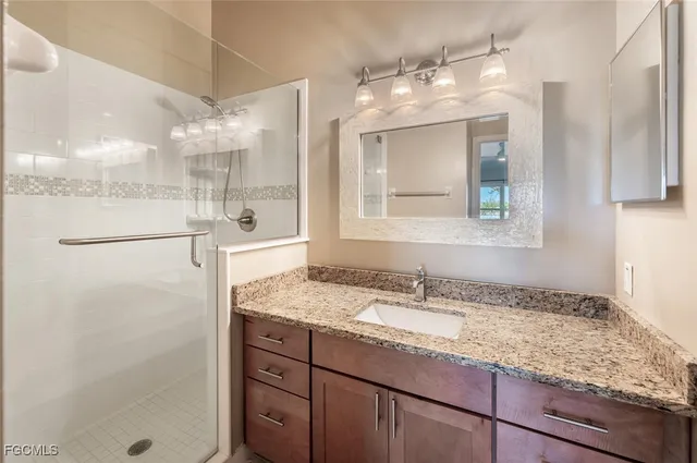 a bathroom with a granite countertop sink mirror and a shower