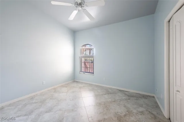 an empty room with a chandelier fan and windows