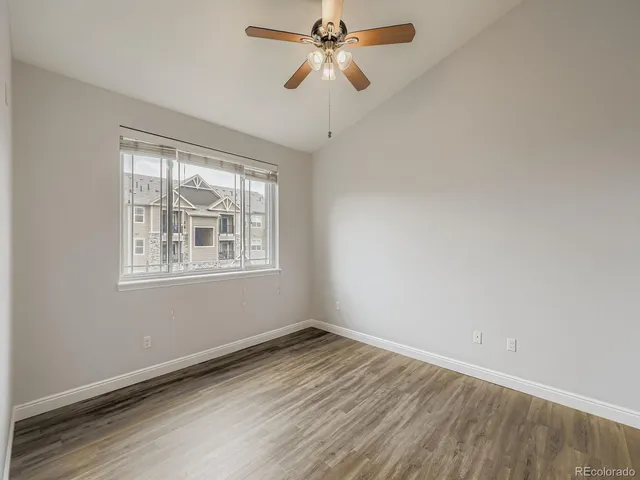 a view of empty room with wooden floor and fan