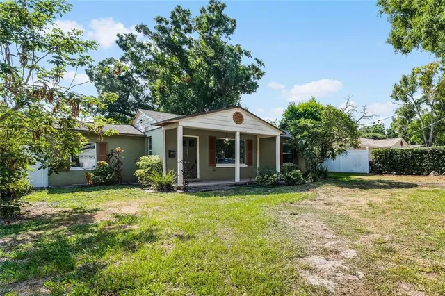 a front view of a house with a garden and trees