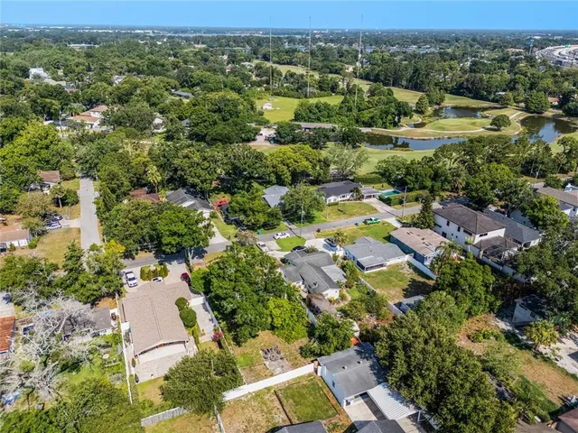 an aerial view of residential houses with outdoor space and trees