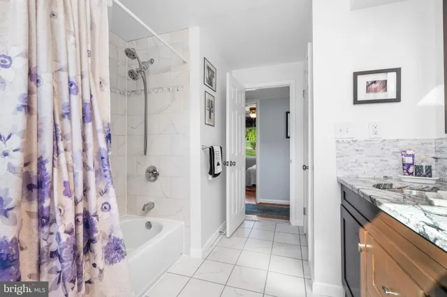 a bathroom with a granite countertop sink a mirror a bathtub and shower