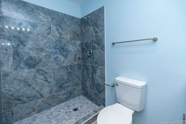 a white toilet sitting next to a shower