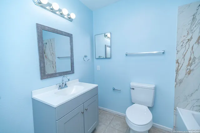 a bathroom with a toilet a sink a mirror and vanity