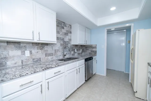 a kitchen with granite countertop a sink stainless steel appliances and cabinets