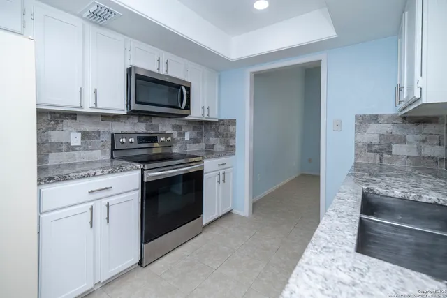 a kitchen with stainless steel appliances granite countertop white cabinets and a stove
