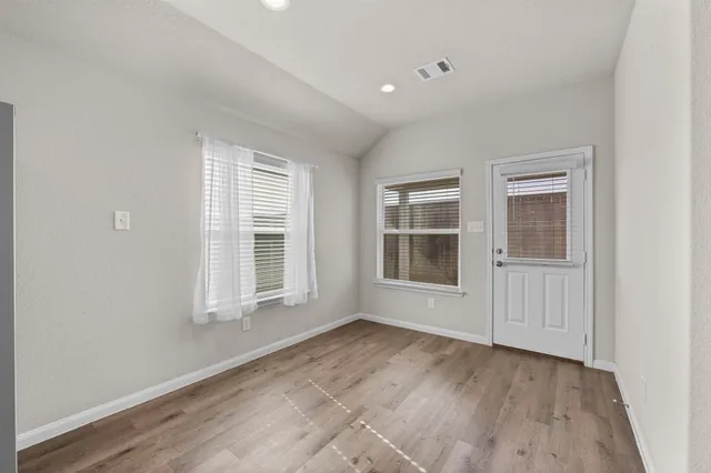 an empty room with wooden floor and windows