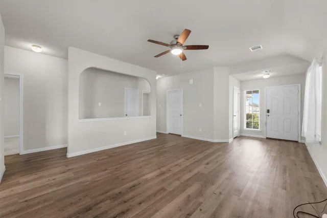 a view of empty room with wooden floor and window