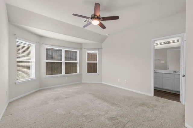 a view of an empty room with a window and kitchen view