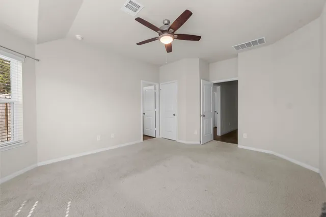 an empty room with closet and ceiling fan