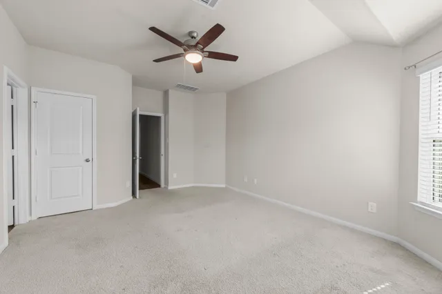 an empty room with chandelier fan and windows