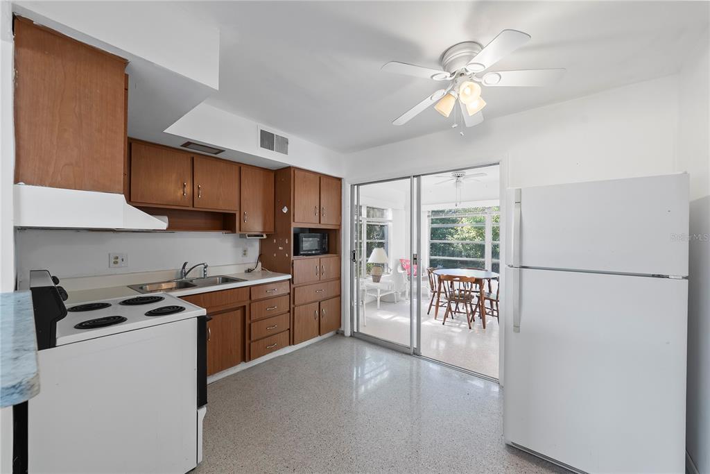10609 Raffia Drive Port Richey, FL 34668 - Photo 7 of 24 a kitchen with stainless steel appliances a refrigerator a stove a sink a dining table and chairs with wooden floor