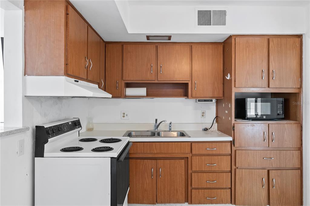 10609 Raffia Drive Port Richey, FL 34668 - Photo 8 of 24 a kitchen with stainless steel appliances wooden cabinets and a stove top oven