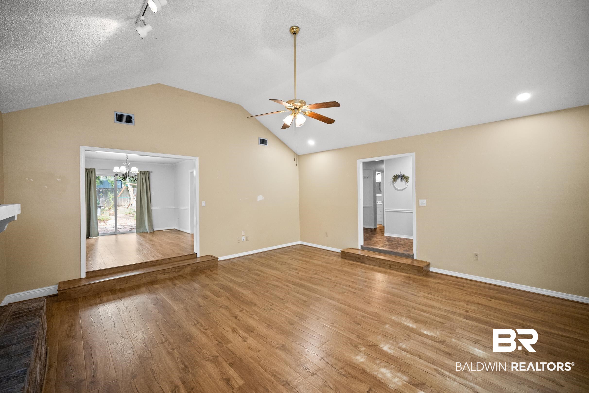 123 Dunbar Loop Daphne, AL 36526 - Photo 5 of 33 Unfurnished living room featuring a chandelier, hardwood / wood-style floors, lofted ceiling, track lighting, and a ceiling fan