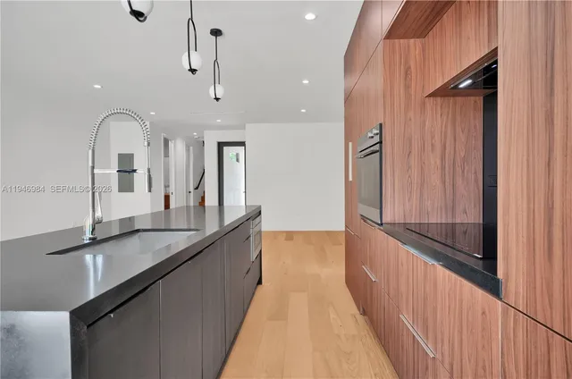 a large kitchen with granite countertop a large counter top space a sink stainless steel appliances and cabinets