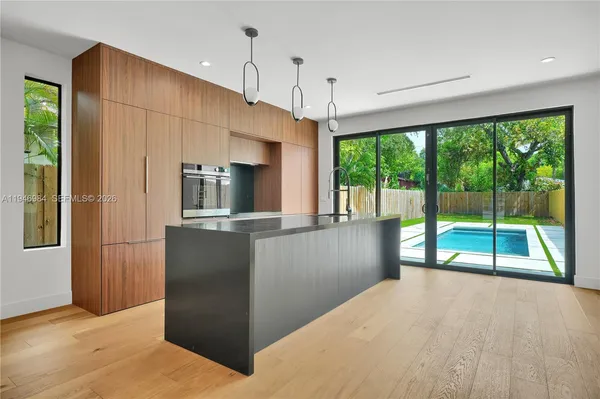 a kitchen with kitchen island a large window cabinets and stainless steel appliances