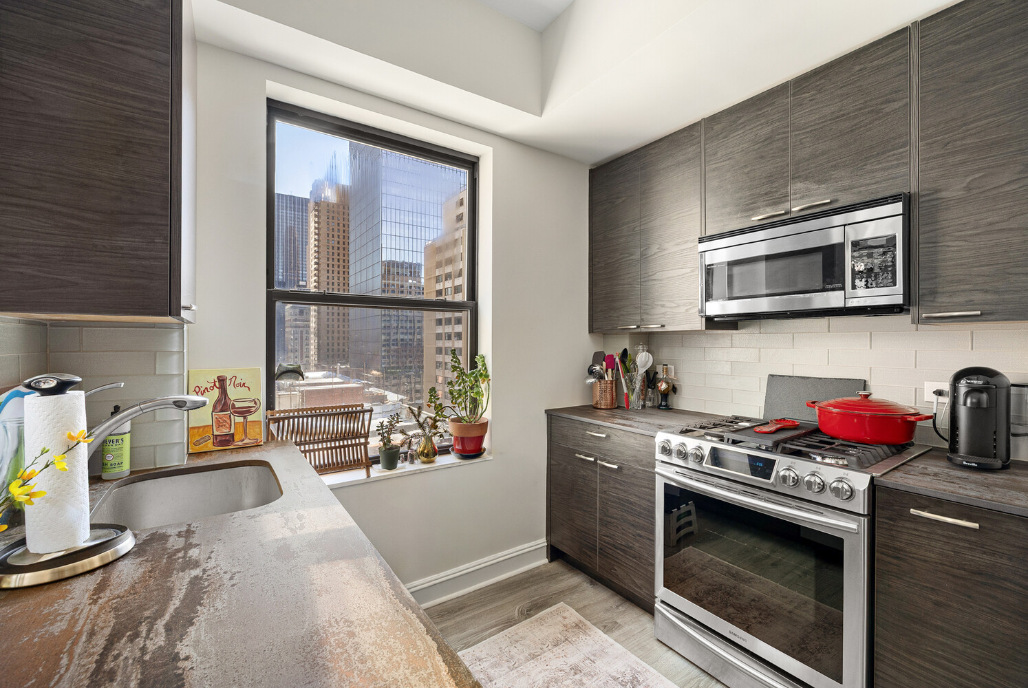 321 West 55th Street, Unit 93 Manhattan, NY 10019 - Photo 6 of 10 a kitchen with stainless steel appliances a stove a sink and a microwave
