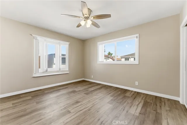 a view of an empty room with a window and wooden floor