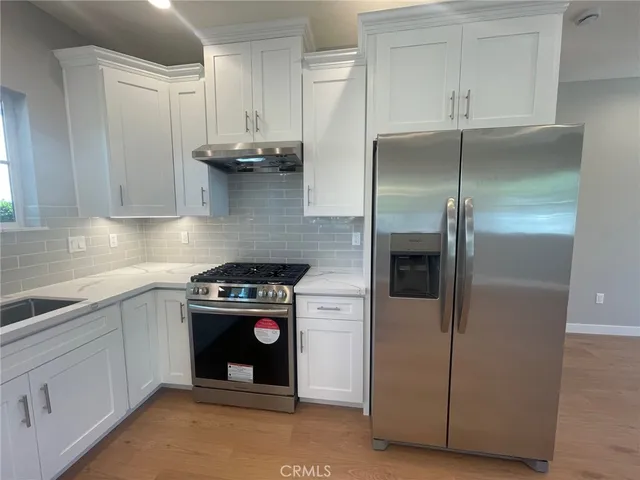 a kitchen with stainless steel appliances granite countertop a refrigerator a stove and a sink