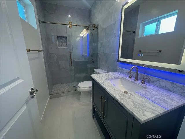 a bathroom with a granite countertop sink a toilet and shower