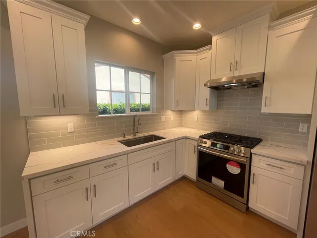a kitchen with stainless steel appliances granite countertop white cabinets and a stove