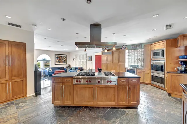 a kitchen with stainless steel appliances granite countertop a stove a sink a oven a dining table and chairs with wooden floor