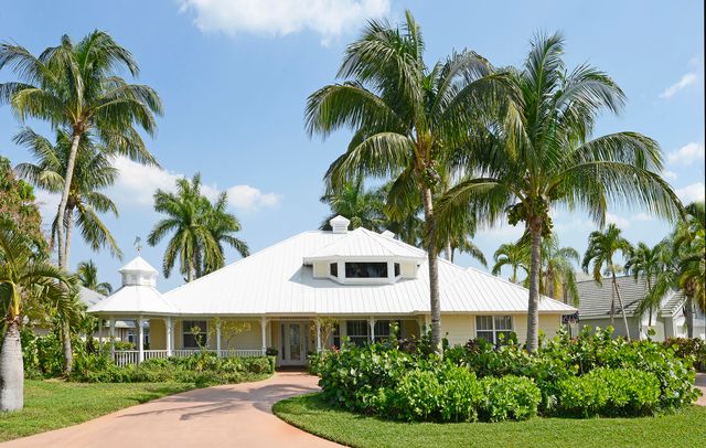 a front view of a house with a lots of palm trees