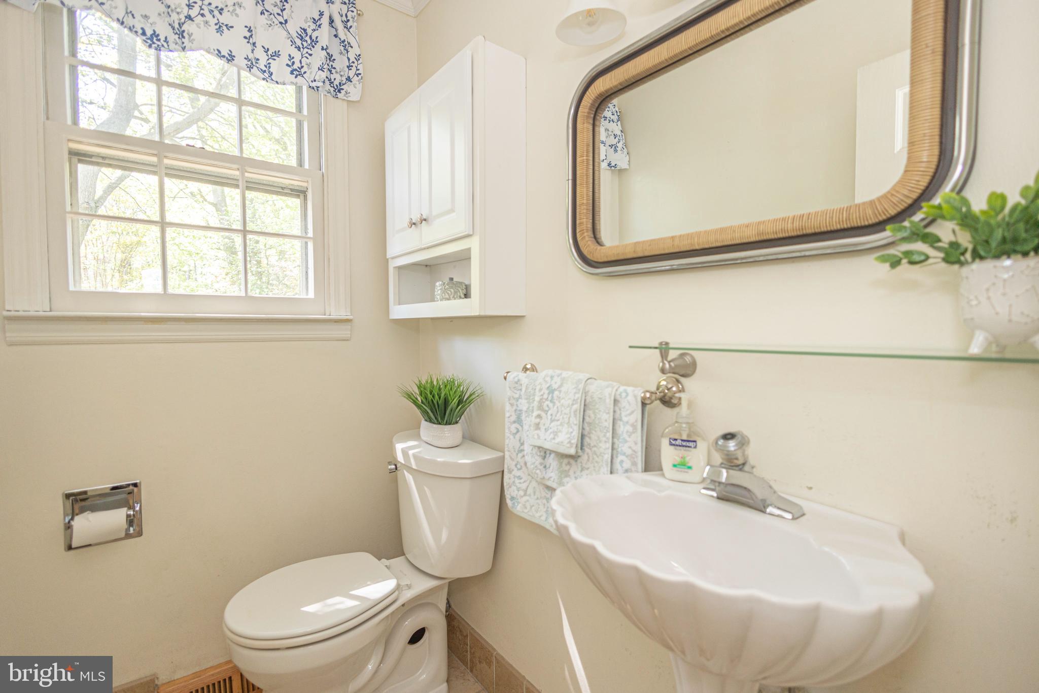 2316 Shipley Road Wilmington, DE 19803 - Photo 13 of 42 a bathroom with a sink a mirror a toilet and a window