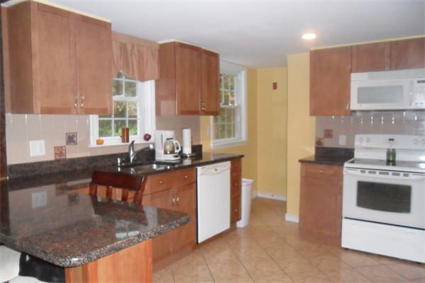 30 Adams Road Ashland, MA 01721 - Photo 7 of 20 a kitchen with kitchen island granite countertop a stove a sink and a refrigerator