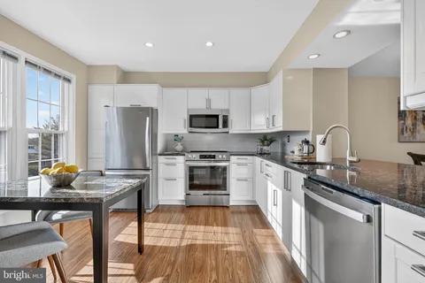 a kitchen with stainless steel appliances a stove a sink dishwasher a refrigerator and a microwave oven with wooden floor