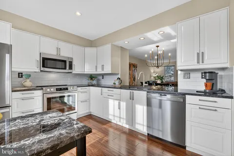 a kitchen with granite countertop white cabinets and black stainless steel appliances