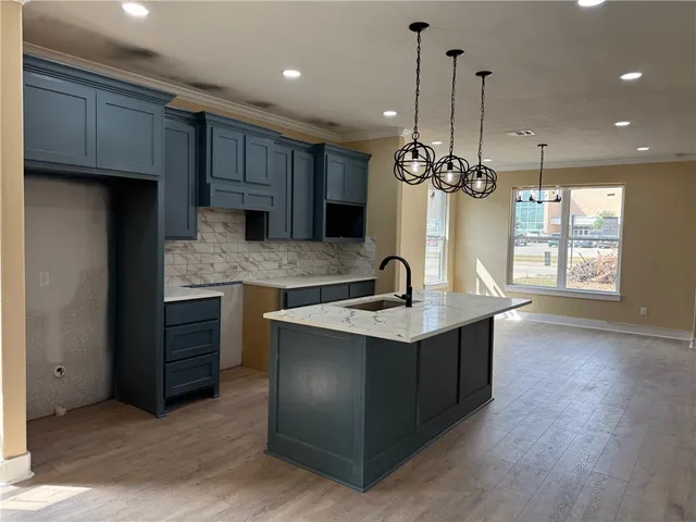 a kitchen with stainless steel appliances granite countertop a sink a stove and a wooden floors