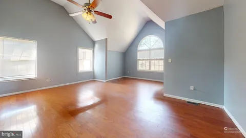 a view of empty room with wooden floor and fan