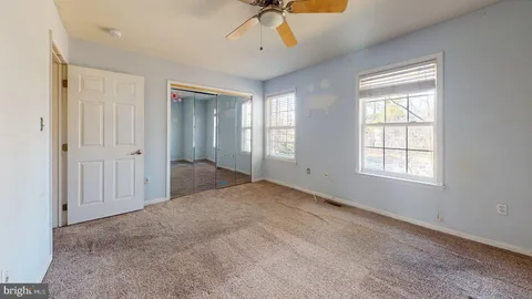 an empty room with chandelier fan and windows