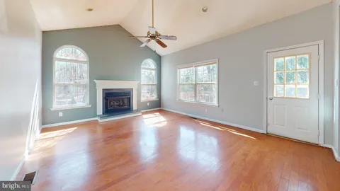 an empty room with windows fireplace and wooden floor