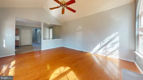 a view of a big room with wooden floor and chandelier fan