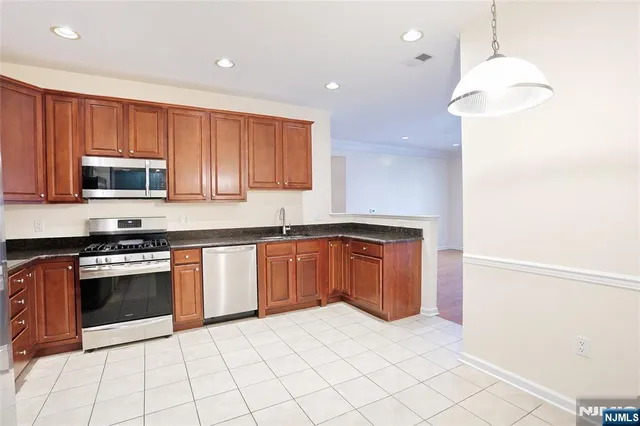 a kitchen with stainless steel appliances granite countertop a refrigerator a stove top oven a sink and dishwasher