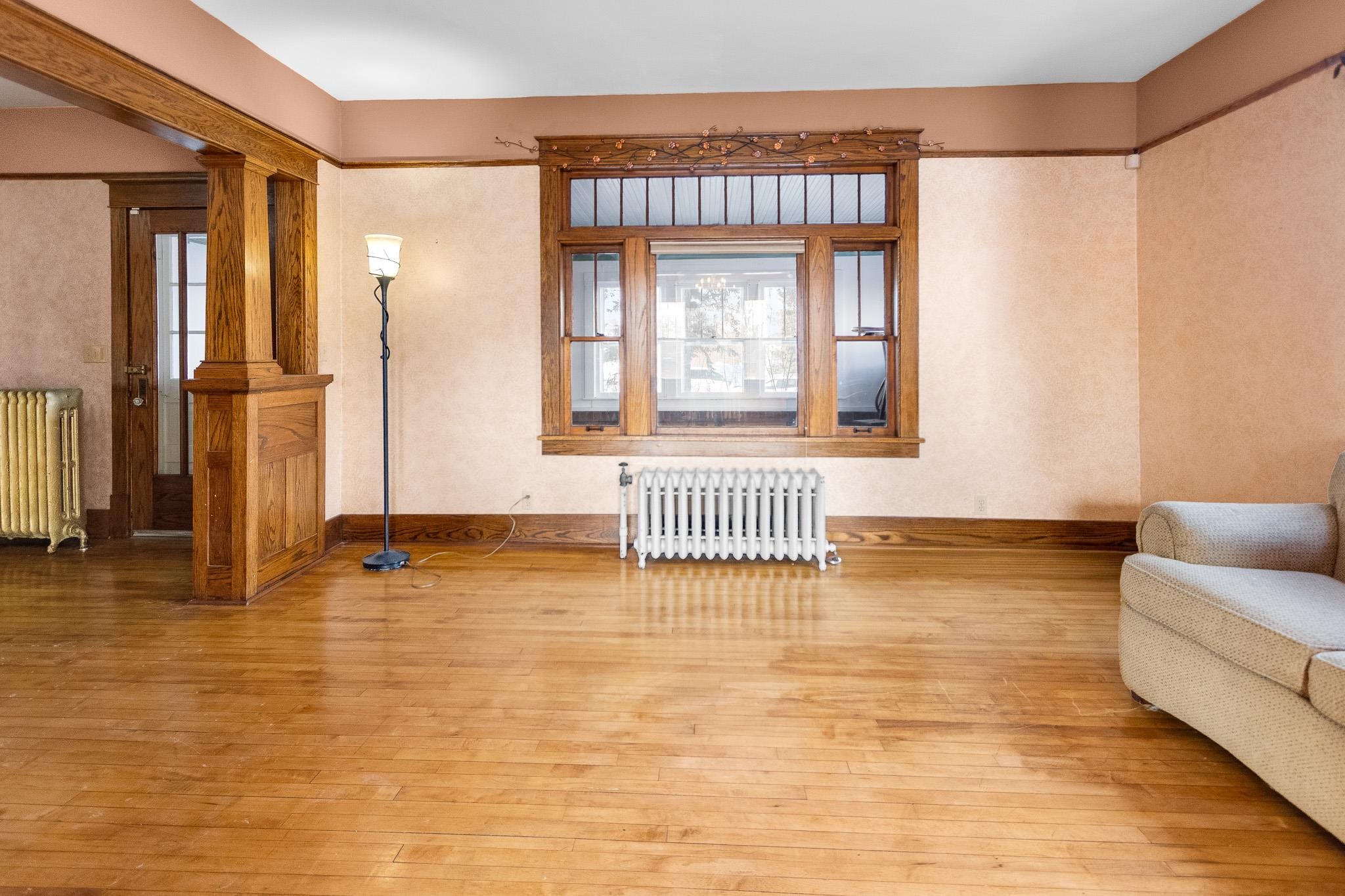 6494 School Street Finlayson, MN 55735 - Photo 9 of 32 Living area featuring hardwood / wood-style flooring, radiator heating unit, ornate columns, and healthy amount of natural light