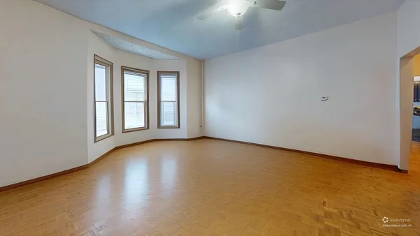 a view of an empty room with a window and wooden floor